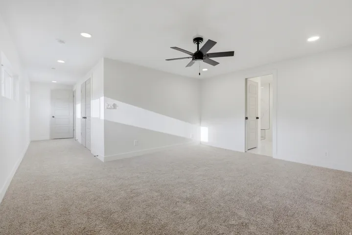 Spacious room featuring neutral carpet, white walls, recessed lighting, and a ceiling fan