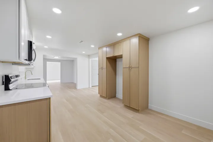 Light wood-finish flooring, white walls, recessed lighting, built-in cabinetry, and white countertops