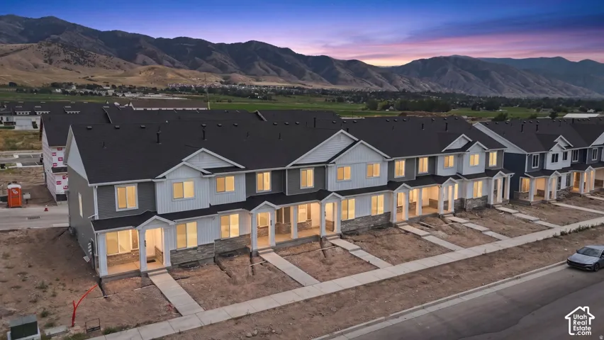 Row of townhomes featuring varied exterior finishes, individual covered entryways, and dark shingle roofing