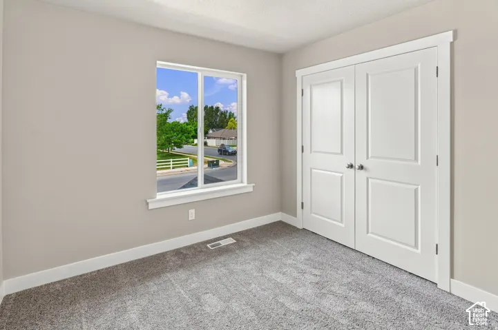 Neutral wall paint, plush carpeting, white trim, white window frame, and bi-fold closet doors