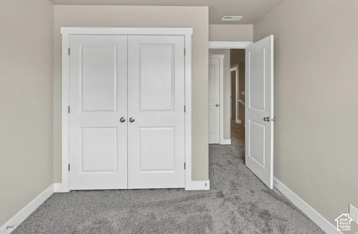 White paneled bifold closet doors, light gray wall paint, white trim, and gray carpeted flooring