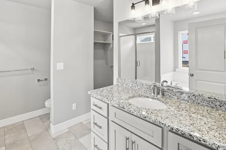Bathroom vanity with a granite countertop, undermount sink, and chrome faucet
