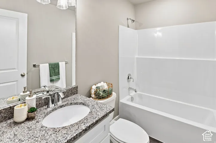 Vanity with granite-style countertop, undermount sink, chrome faucet, and overhead light fixture