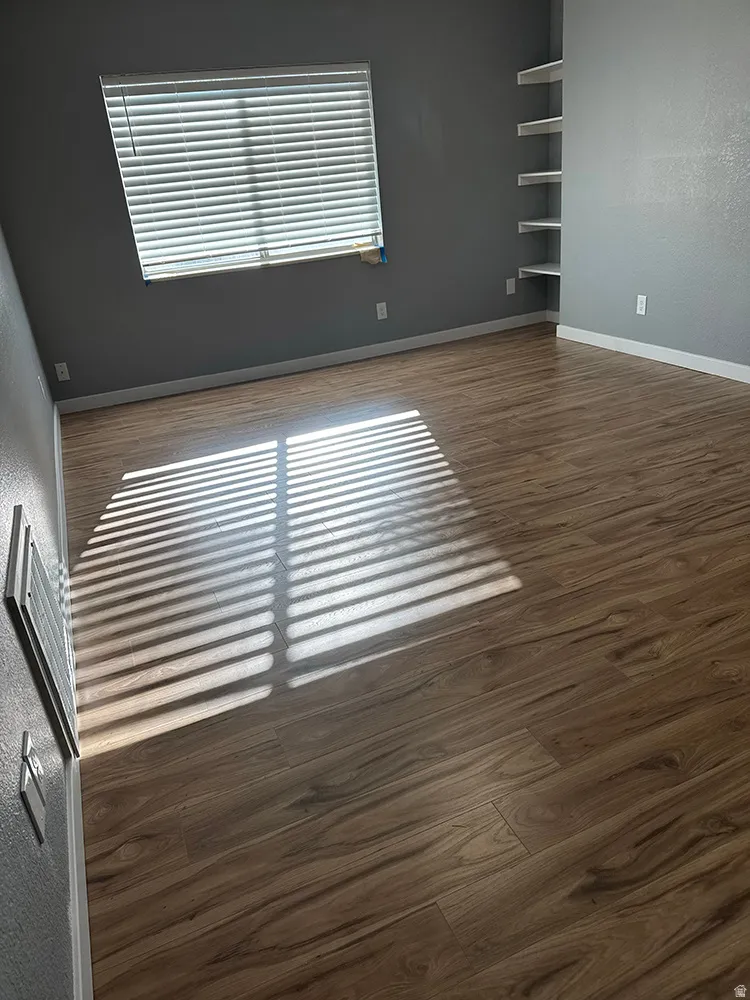 Wood-finish flooring, built-in shelving, and window with blinds