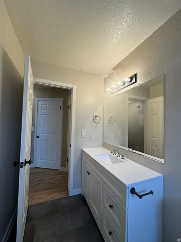 Bathroom vanity featuring a white countertop with an integrated sink, a rectangular mirror, and a five-bulb vanity light fixture