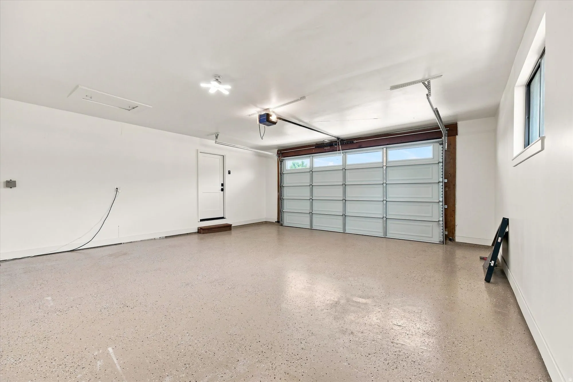 Garage with an epoxy floor, overhead door with transom windows, and a side access door