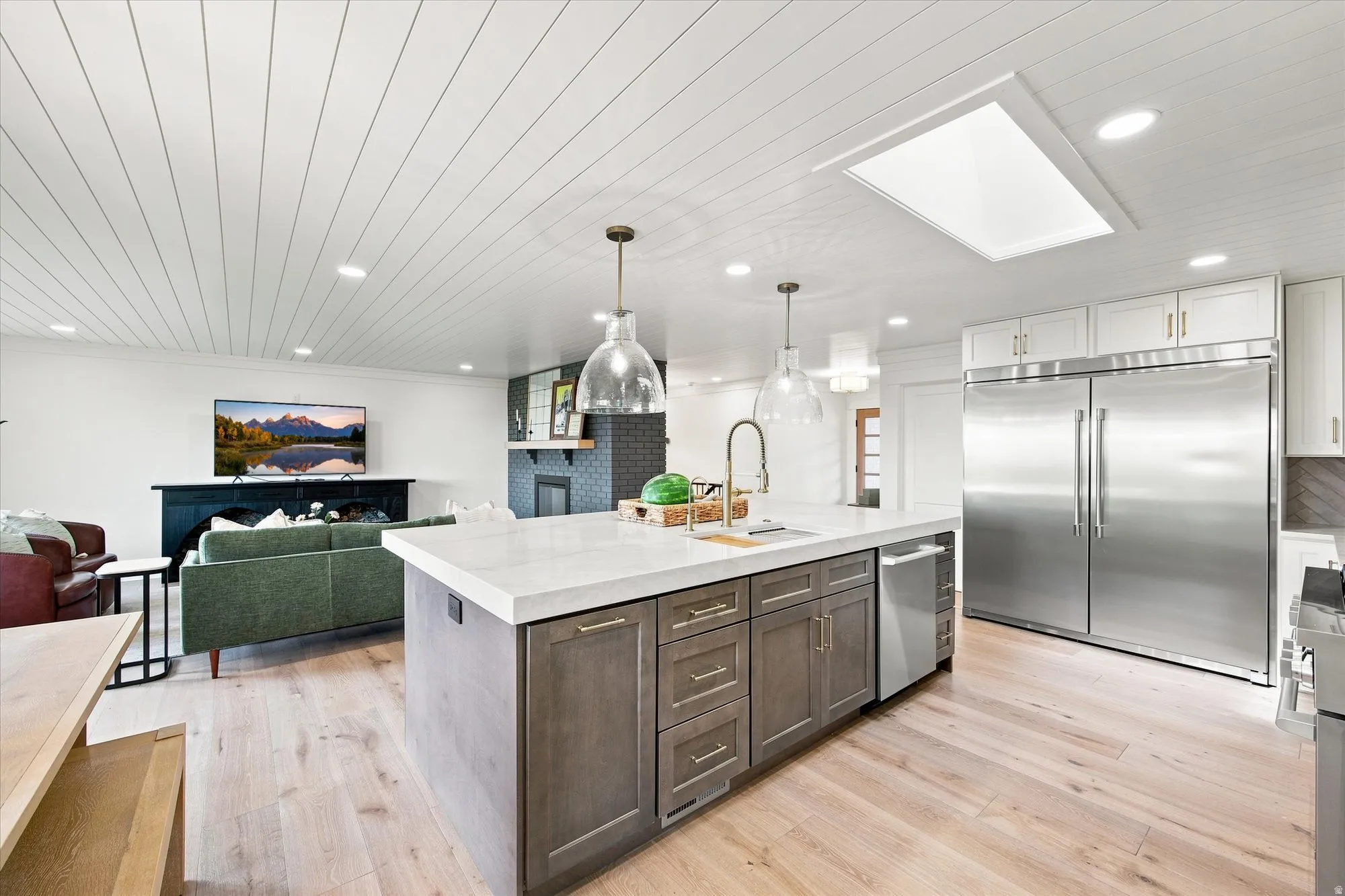 Kitchen island with light-toned countertop, stainless steel refrigerator, wood-finish flooring, and shiplap ceiling