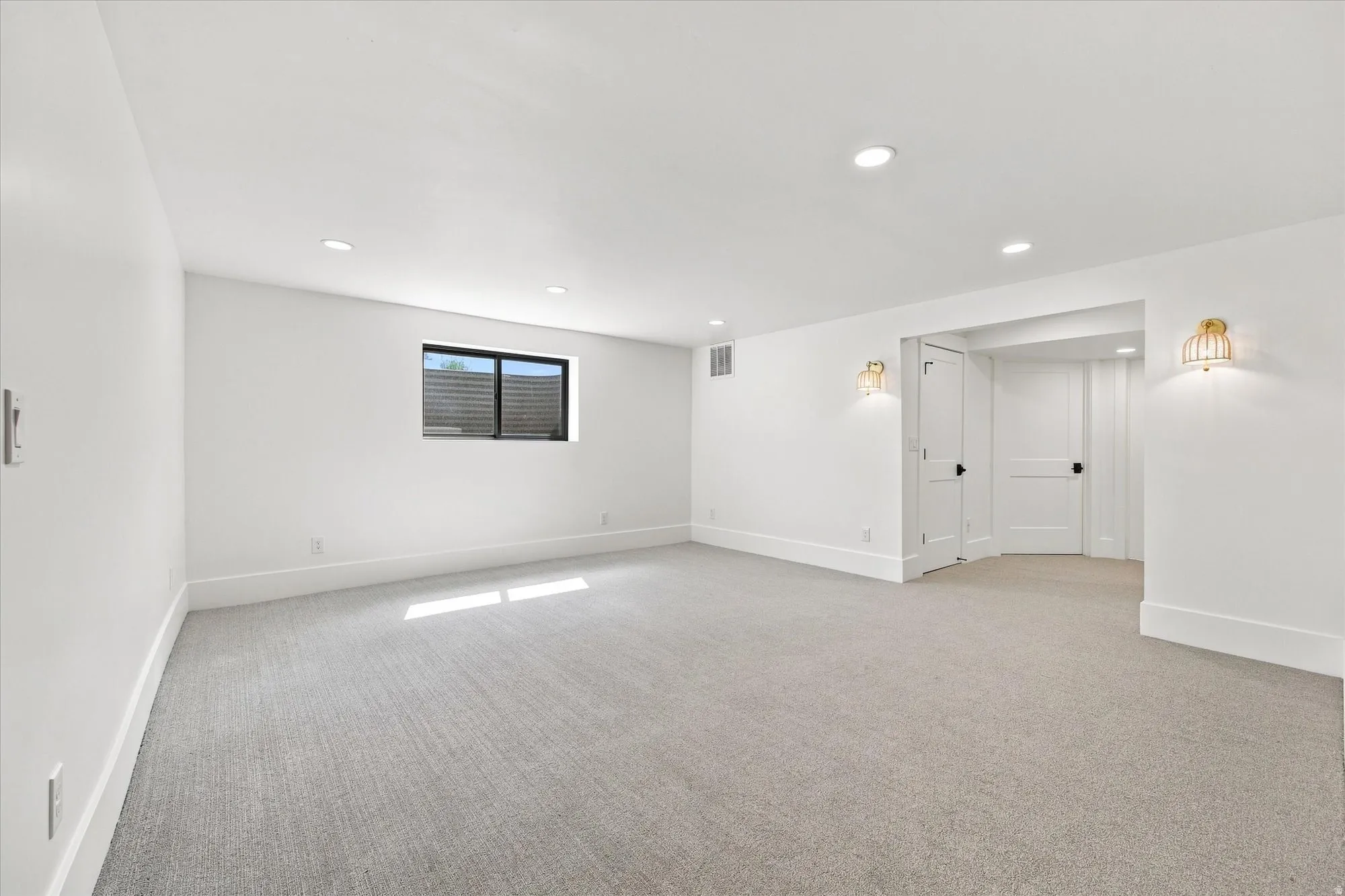 Carpeted flooring with recessed lighting, a window, and wall sconces