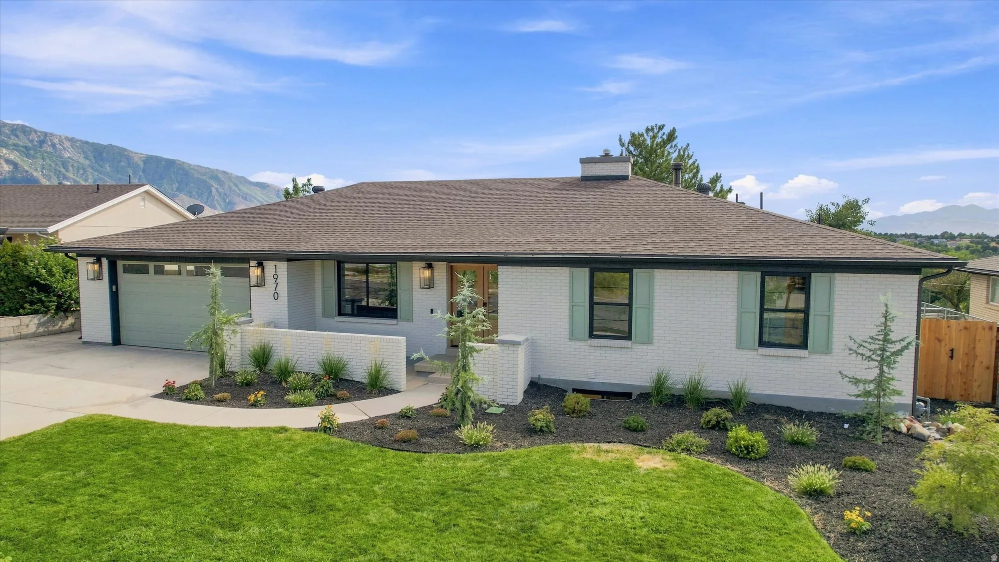 White brick exterior with contrasting dark trim, light green garage door, coordinating window shutters, and a dark shingle roof