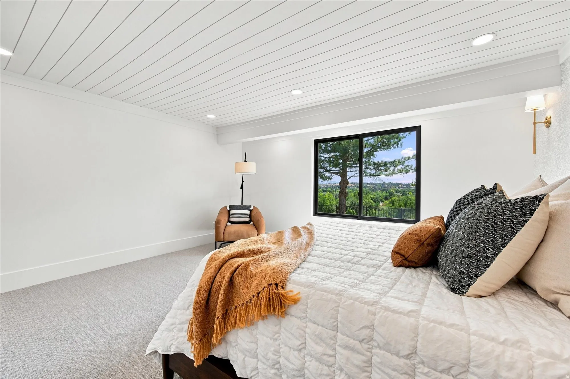 Carpeted flooring, white walls, recessed ceiling lighting, a large window, and a wall-mounted light fixture
