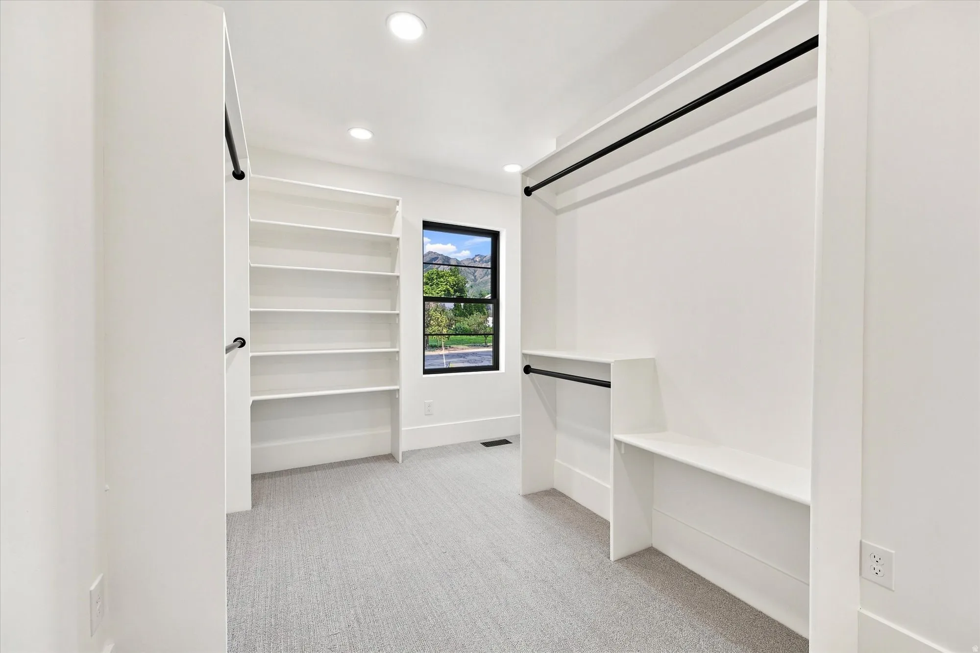 Built-in shelving, integrated hanging rods, recessed lighting, and a window with black trim