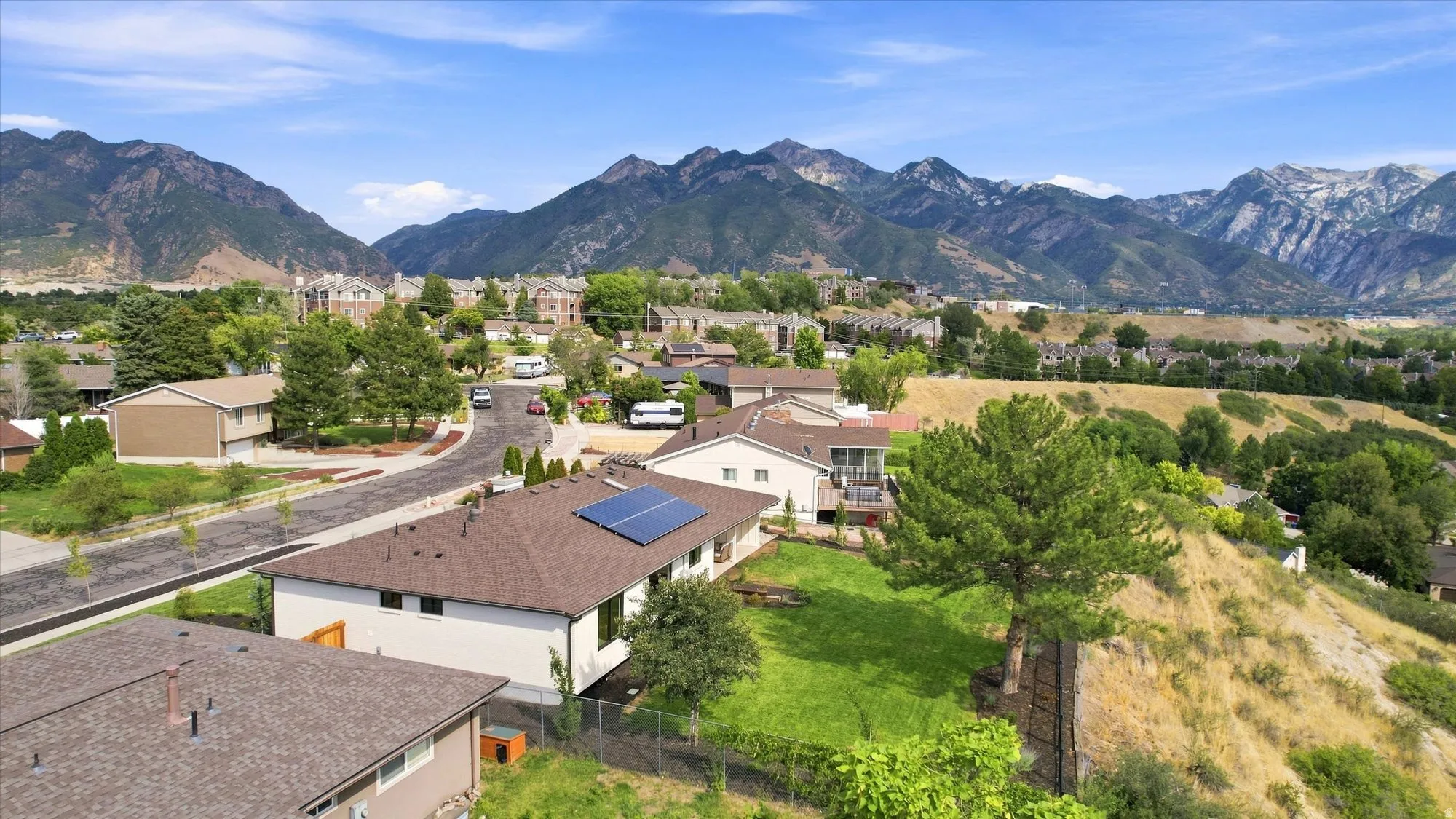 Residential property featuring a brown shingle roof, solar panel installation, and a manicured lawn