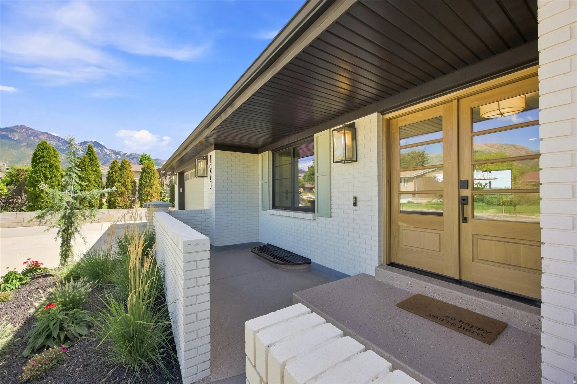 Entry features double wood doors with glass panels, a brick exterior, and an exterior wall lantern