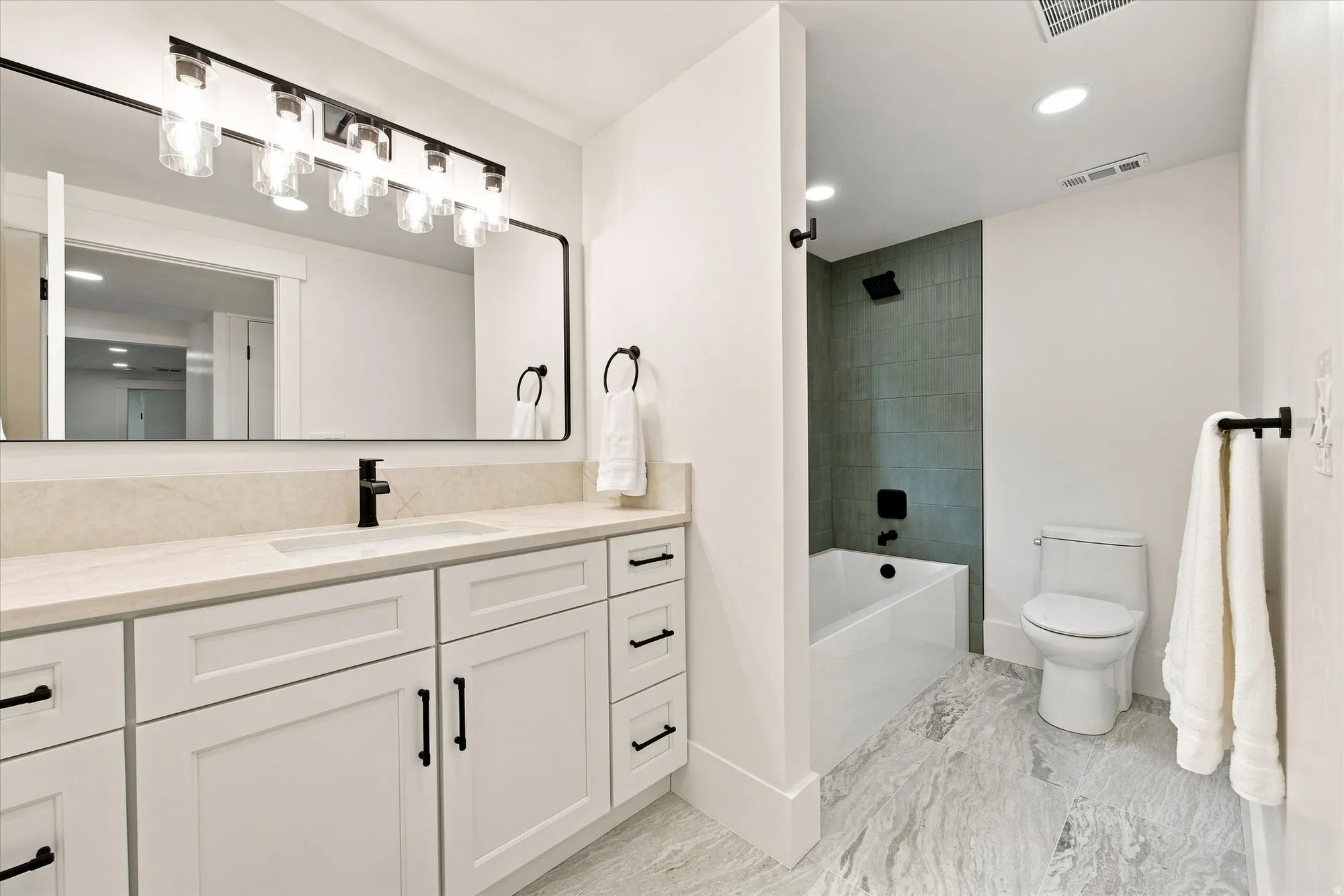 Vanity with white shaker cabinetry, integrated sink, and matte black fixtures