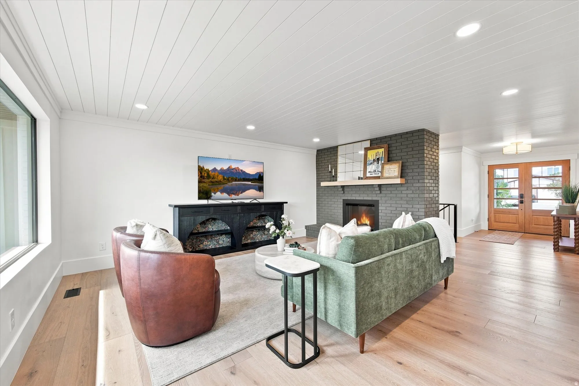 Bright, open living area showcasing hardwood flooring, recessed ceiling lighting, and a gas fireplace with dark tile surround and built-in cabinetry