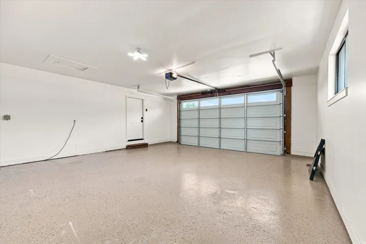 Garage with an epoxy floor, overhead door with transom windows, and a side access door