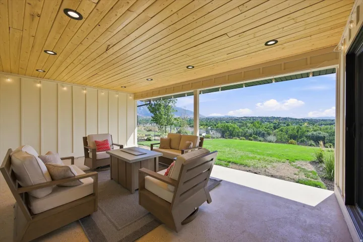 Covered patio featuring a wood-paneled ceiling with recessed lighting, board and batten siding, and a concrete patio floor