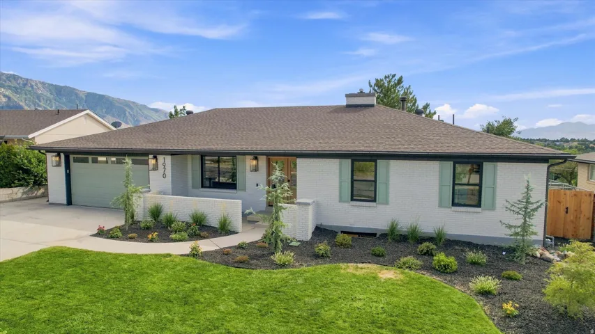 White brick exterior with contrasting dark trim, light green garage door, coordinating window shutters, and a dark shingle roof