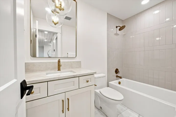 White vanity with gold-finish hardware and a rectangular undermount sink
