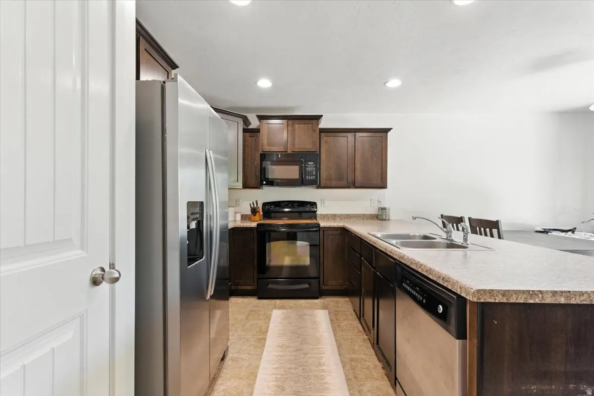 Kitchen featuring dark wood-finish cabinetry, stainless steel appliances, and recessed lighting