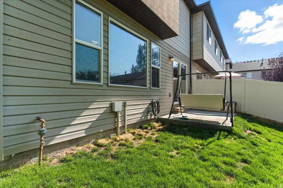 Rear exterior with light-colored siding, a concrete patio, and a white fence