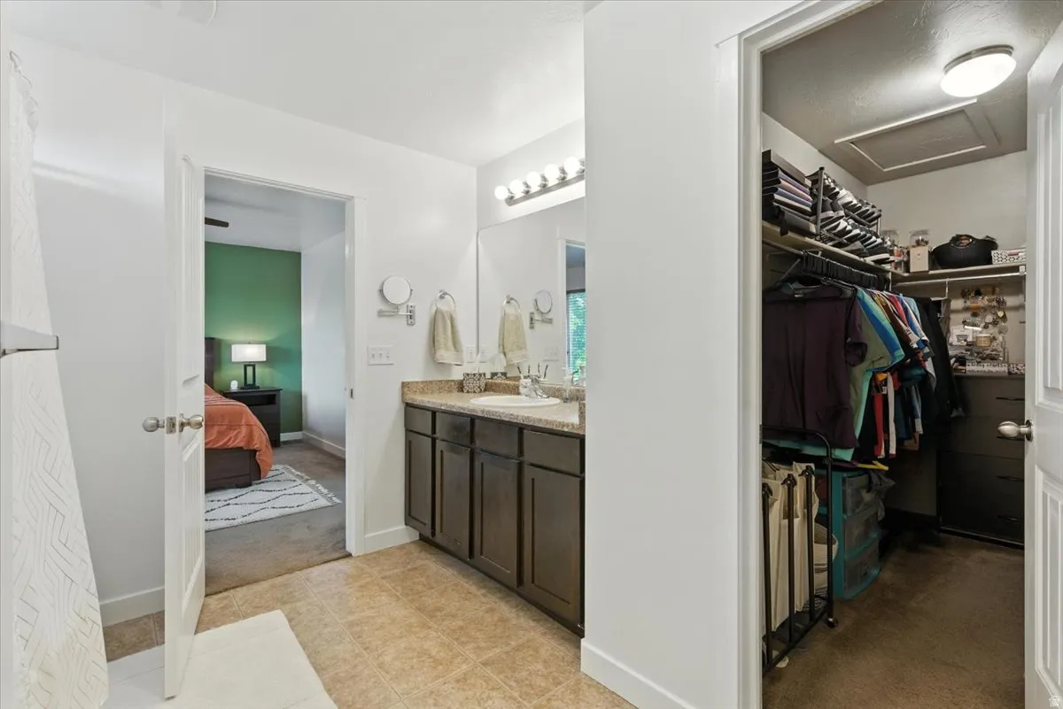 Built-in vanity with a single basin sink, wall-mounted mirror, and overhead lighting