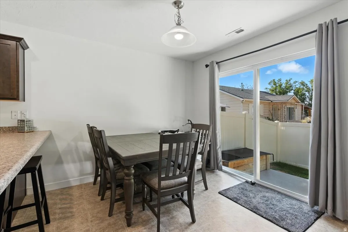 Dining area featuring ceramic tile flooring, a sliding glass door, and a built-in breakfast bar with a speckled countertop