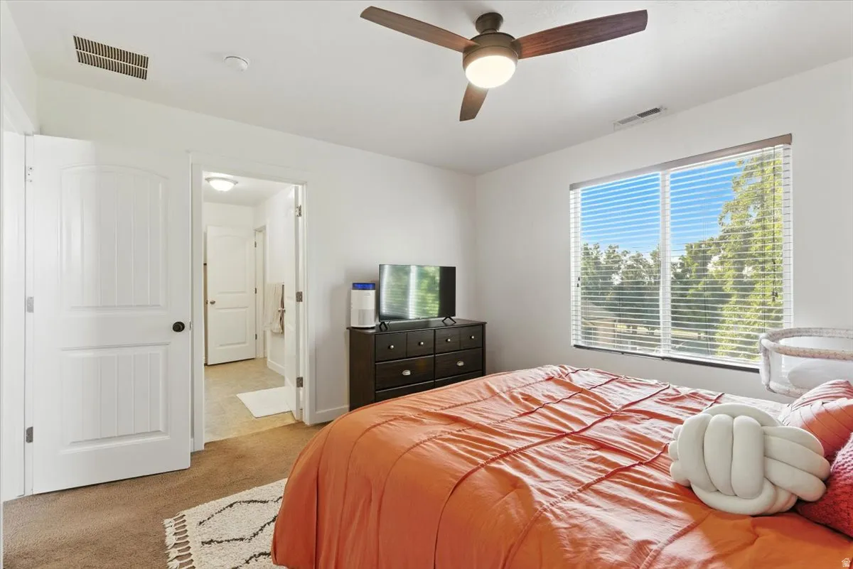 White interior walls with a ceiling fan, a large window with horizontal blinds, and carpeted flooring