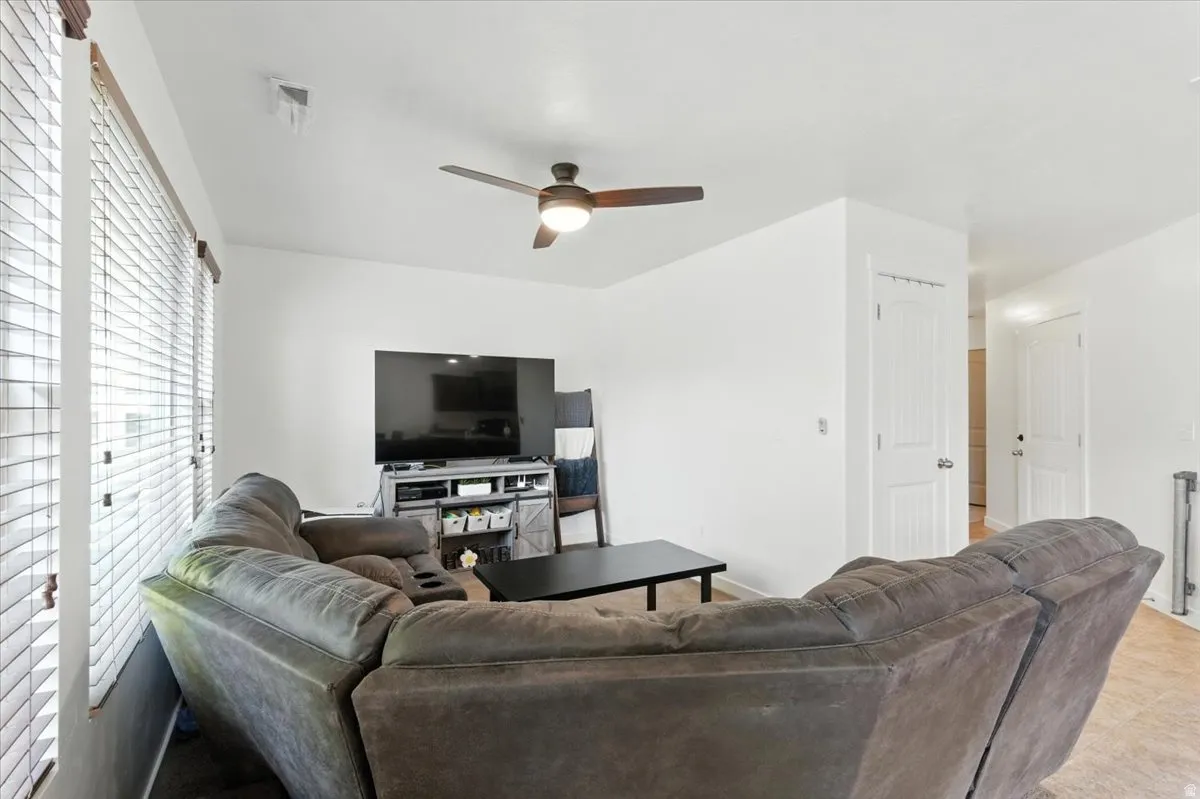 White walls with window blinds, a ceiling fan with integrated lighting, and multiple interior doorways