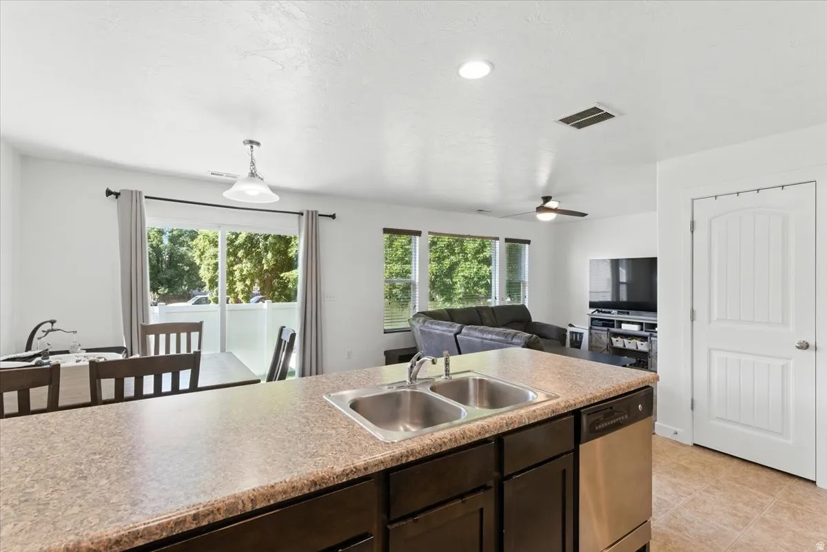 Kitchen island with a double stainless steel sink, integrated dishwasher, and textured countertop