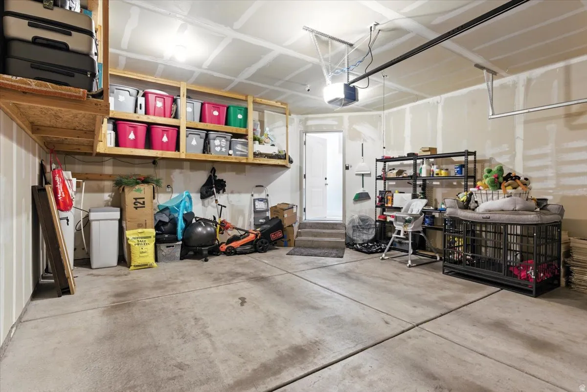Concrete flooring with overhead storage shelving, built-in wall shelving, and an interior access door