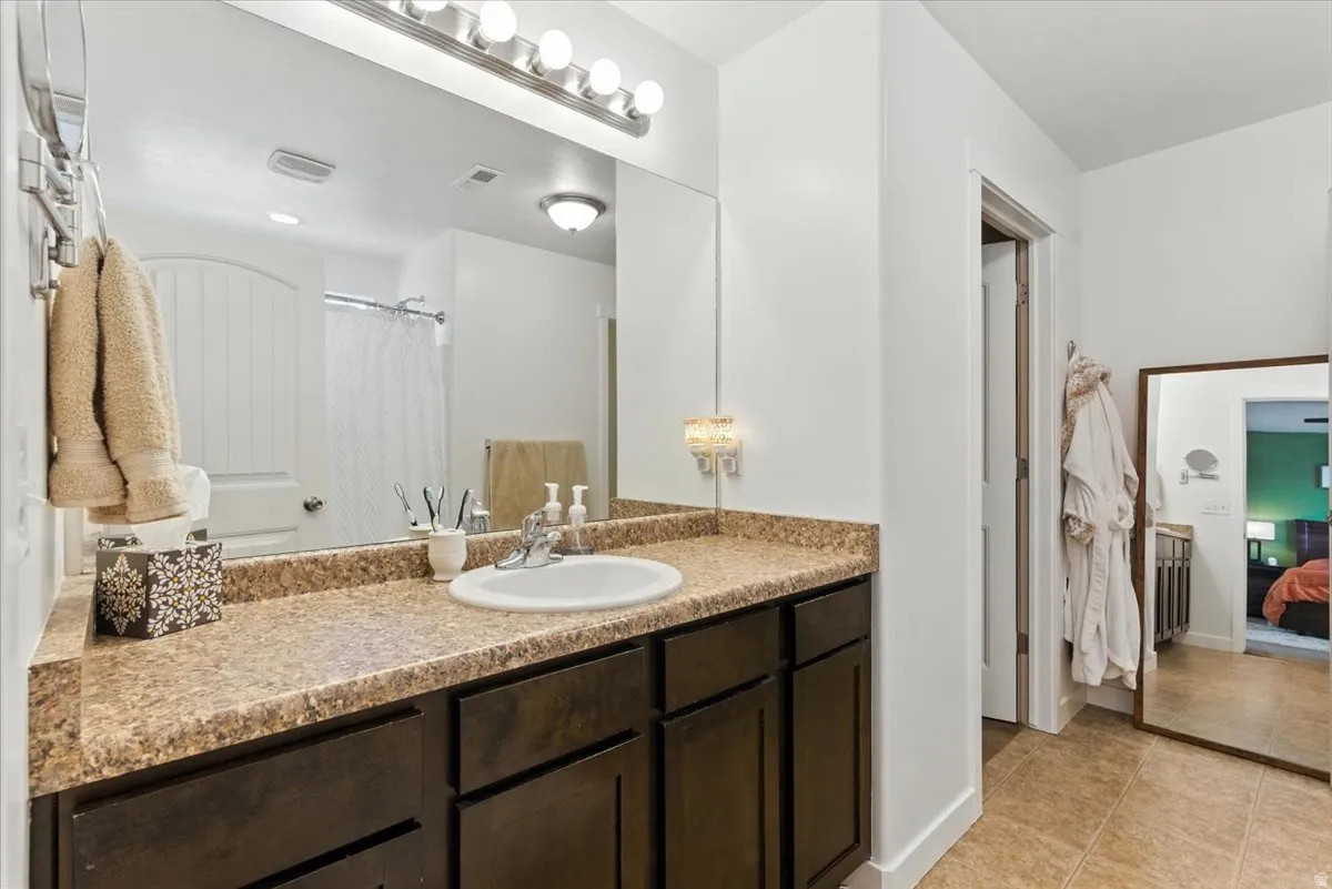 Bathroom featuring a single vanity with dark wood-finish cabinetry, a white basin, and a speckled countertop