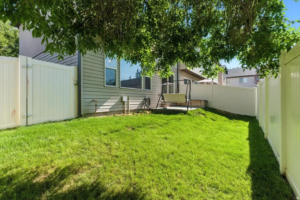 Expansive backyard featuring a manicured lawn, full privacy fencing, and a built-in patio