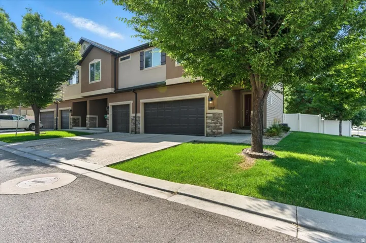 Stucco exterior with stone accents, attached two-car garage, concrete driveway, front entrance, and maintained lawn