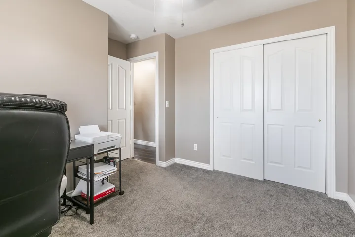 Gray carpeted flooring, light neutral-toned walls, white trim, white paneled bifold closet doors, and a white paneled interior door