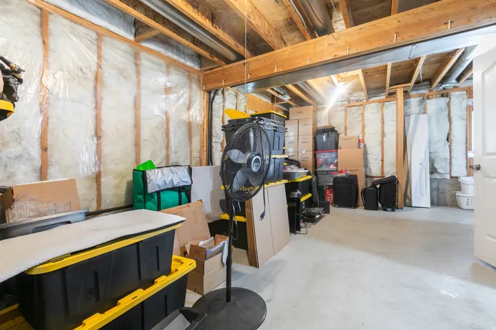 Unfinished basement with exposed wooden joists and concrete flooring