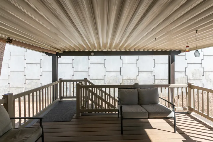 Covered patio with a corrugated ceiling, wood-finish decking, and light-toned railings