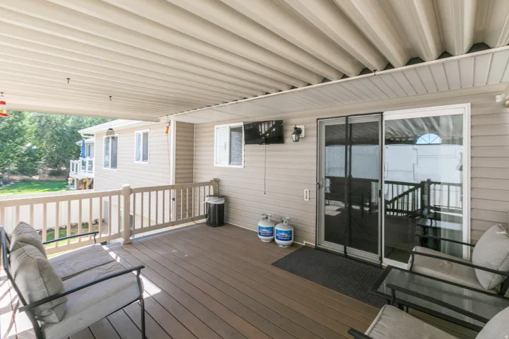 Expansive covered deck featuring composite decking, white railing, and sliding glass door access