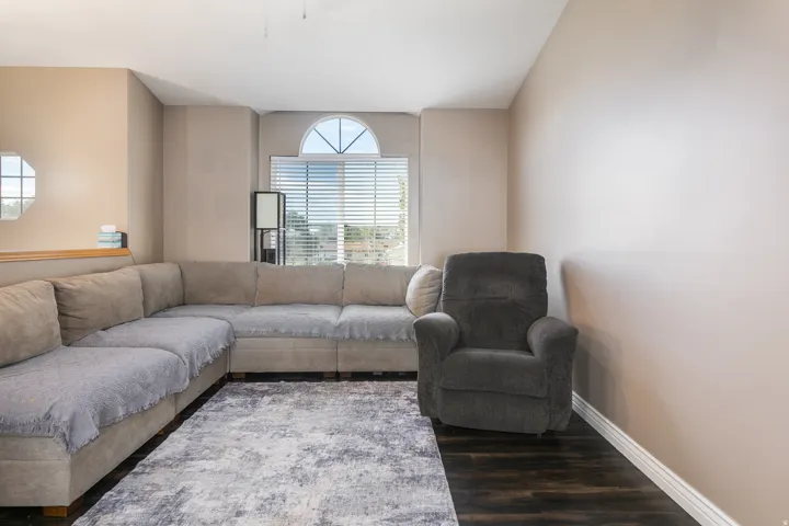 Arch-top window with horizontal blinds, dark wood-finish flooring, and neutral wall tones