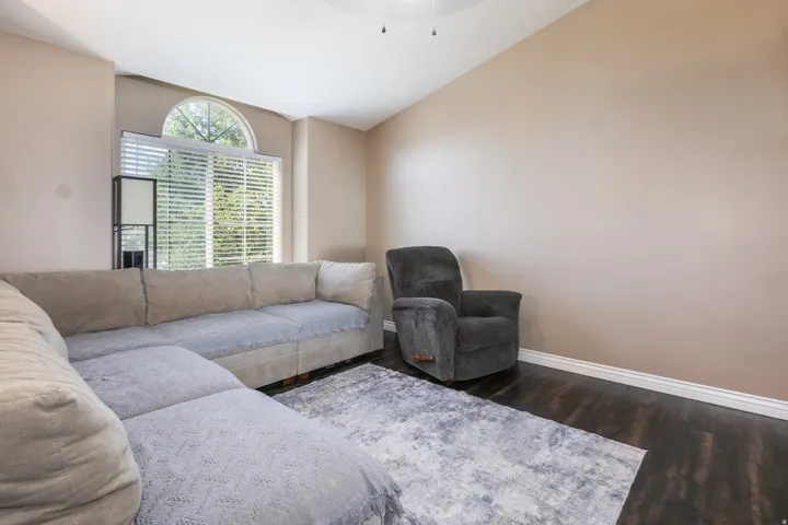 Vaulted ceiling with a ceiling fan, arched window, and dark wood-finish flooring