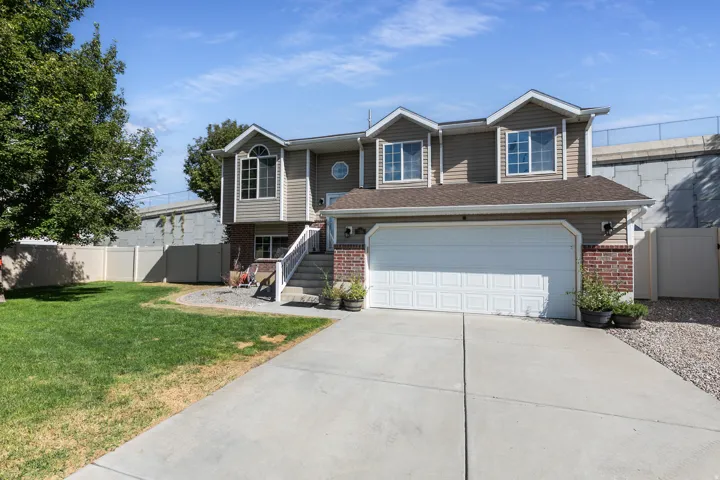 Split-level residence featuring brick and siding facade, an attached two-car garage, concrete driveway, and a fenced yard