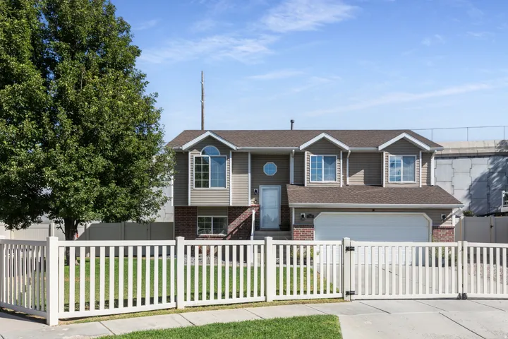 Two-story colonial home featuring a clean facade with board-and-batten siding in gray and white tones, accented by three front-facing windows with blue trim and a matching blue entry door