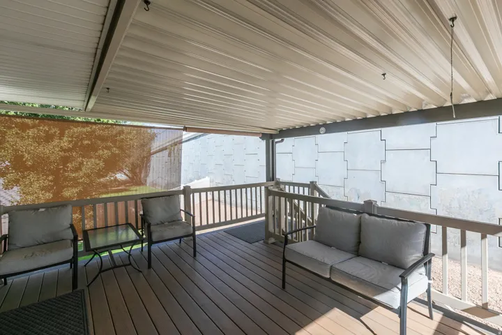 Expansive covered deck featuring wood-finish decking, protective railing, and a corrugated ceiling