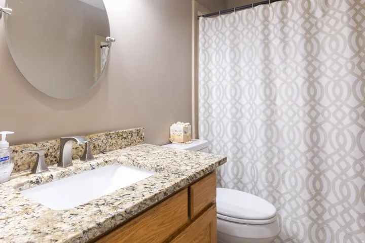 Vanity with a granite-style countertop, undermount sink, and brushed nickel fixtures