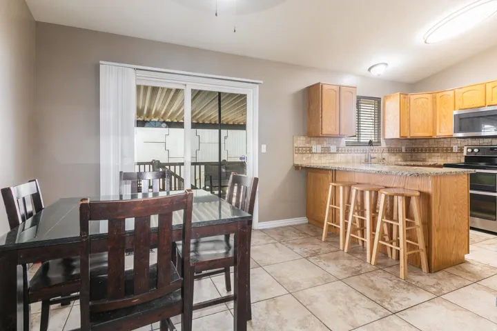 Kitchen featuring wood cabinetry, granite countertops, stainless steel appliances, and a tile backsplash