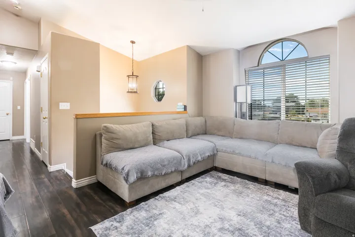 Vaulted ceiling with an arched window, wood-finish flooring, and a decorative pendant light fixture