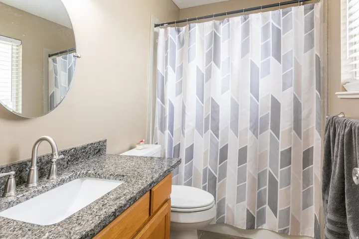 Bathroom vanity featuring a vessel sink, brushed nickel faucet, and a granite-pattern countertop
