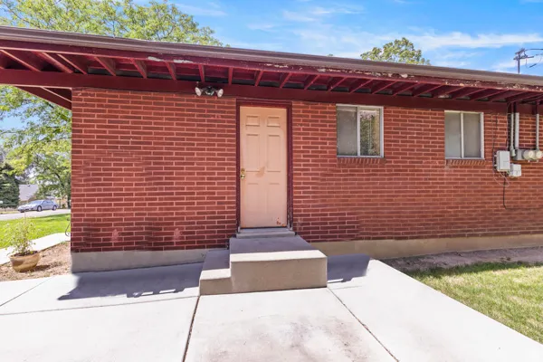Brick exterior with a covered entry, concrete walkway, and exterior lighting