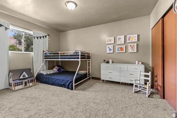 Wall-to-wall carpeting, window with natural light, built-in closet with sliding doors, and overhead lighting