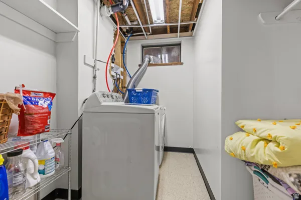 Laundry area featuring permanent shelving, exposed ceiling joists, and a utility window